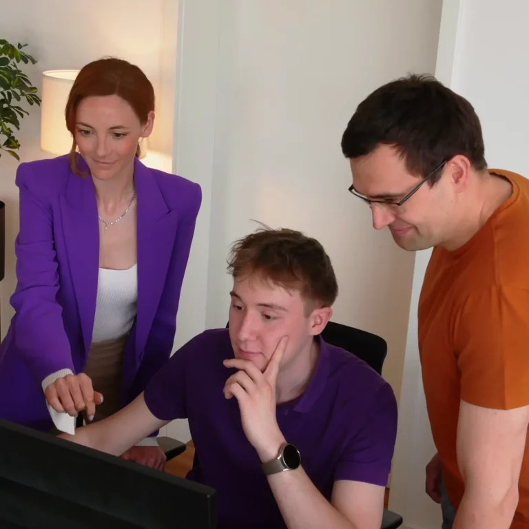 Zwei Personen unterst&uuml;tzen eine Person am Computer.